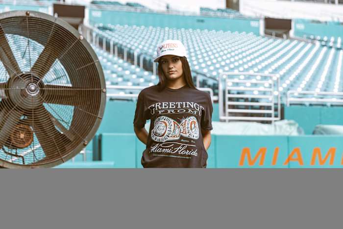 A woman models Miami Dolphins apparel on a football field.